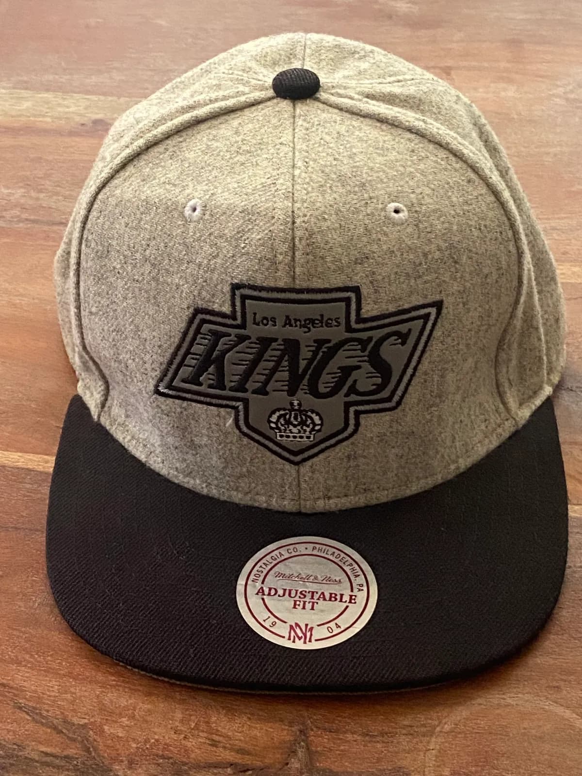Gorra Mitchell & Ness Los Angeles Kings gris con visera negra, ajustable.