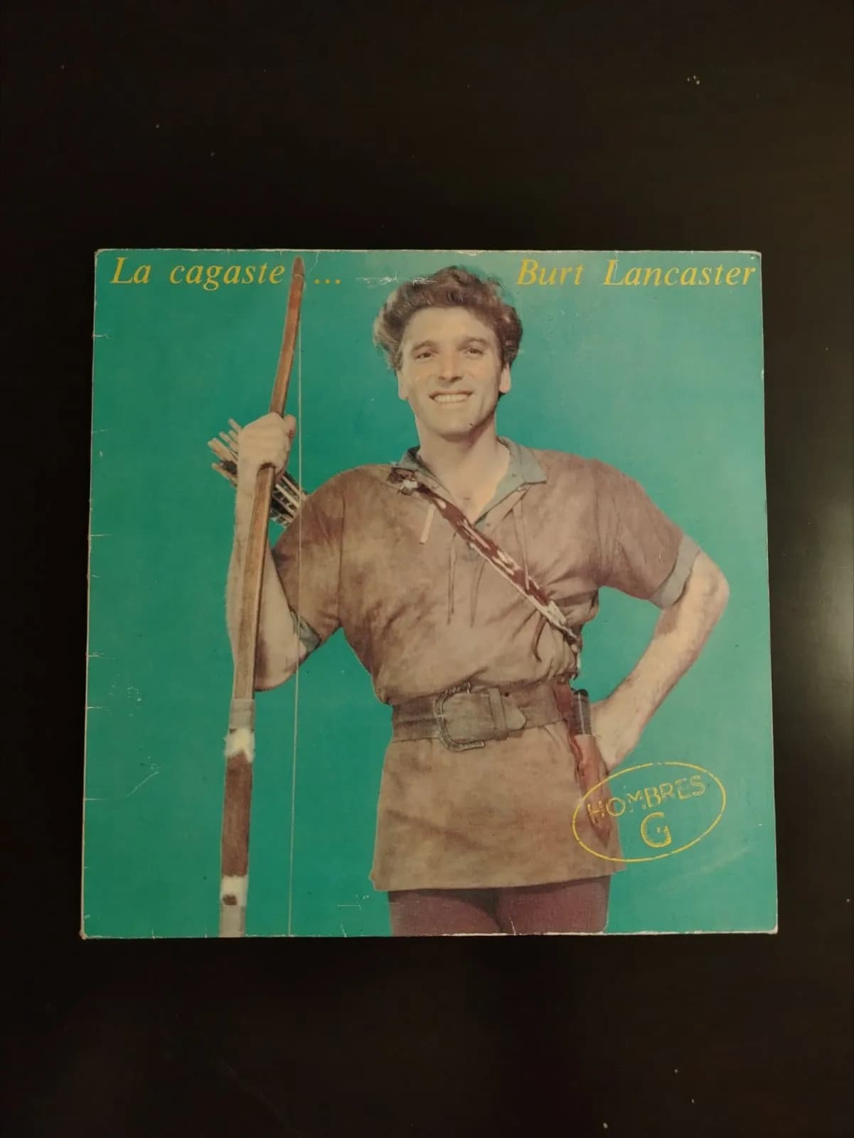 Portada de álbum Hombres G La cagaste... con Burt Lancaster sonriente de arquero.