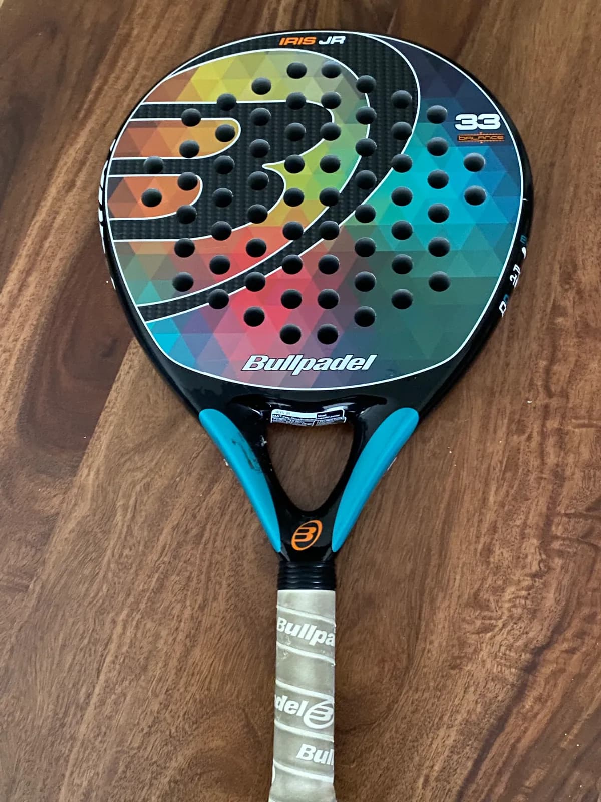 Pala de pádel Bullpadel Iris Jr usada, con diseño de triángulos de colores y puño desgastado.