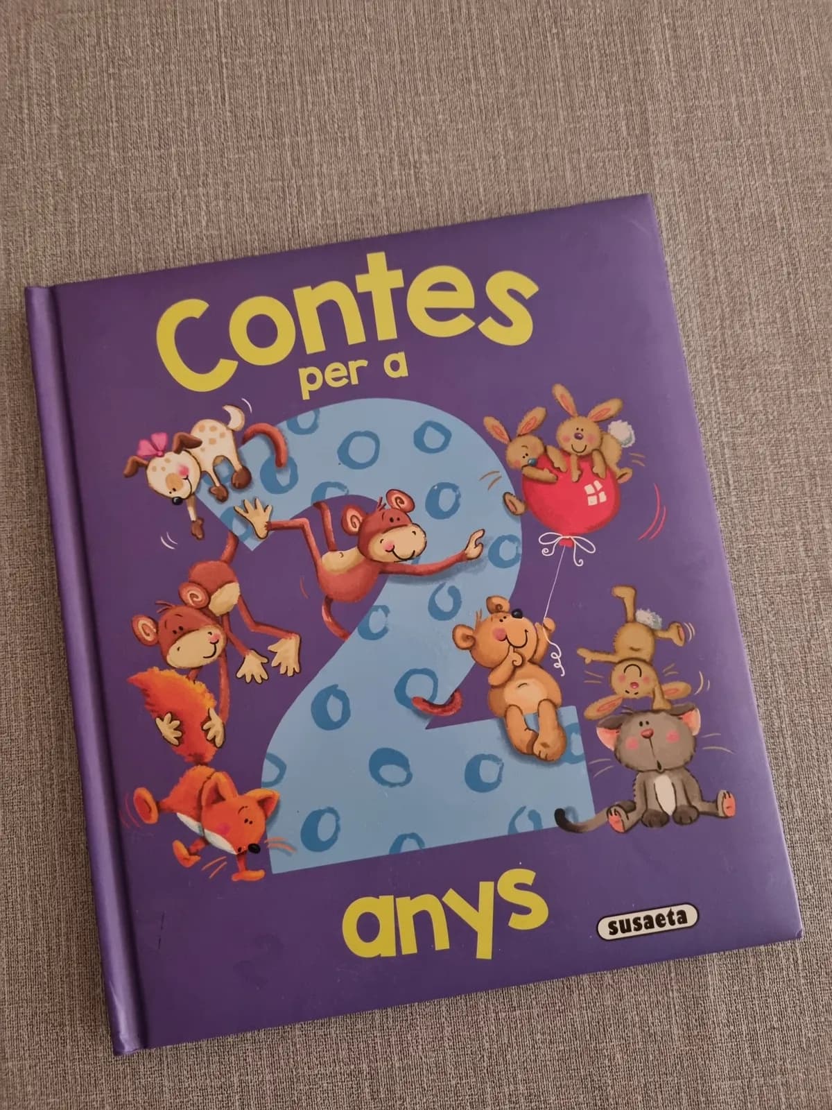 Libro infantil usado "Contes per a 2 anys" con cubierta morada, animales y el número 2.